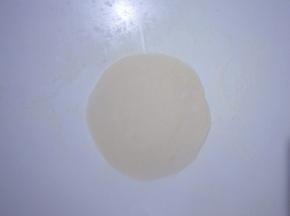 取一个小面团，揉圆按扁擀成中间厚周边薄的面皮儿