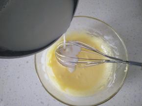 3牛奶加热倒入蛋黄液里，一边倒入一边不停搅拌。