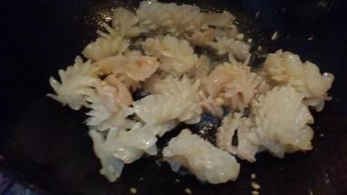 锅里放油烧5成热下鱿鱼卷蒜茸煸炒淋料酒。