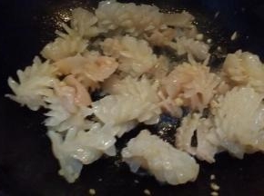 锅里放油烧5成热下鱿鱼卷蒜茸煸炒淋料酒。