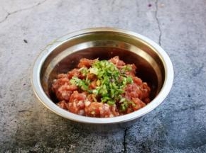 放入葱花，在葱花上滴入1小勺的食用油，用油将葱花拌匀，然后将葱花与肉馅搅拌均匀备用。