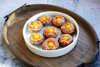 将填满肉馅的香菇放在一个平盘子里，在每个酿好肉馅的香菇上磕入一个鹌鹑蛋。