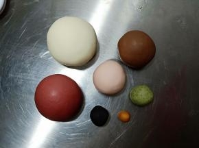 将主材料混合揉成超级无敌光滑的面团后分别揉出32克巧克力面团，25克粉面团，50克红色面团，5克绿色面团，5克黑色面团，1克黄色面团，剩余的白面团备用