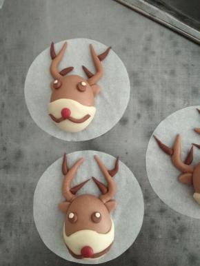 按照上面的图，用圆形模具压出眼睛和鼻子，深可可面团揉成条，做成胡须。