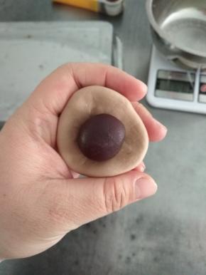 100克浅色可可面团切割成3个30克面团，揉光滑，包入10克的豆沙馅