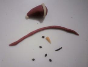 把奥利奥的面团搓成芝麻大小的点(20个)，搓4个小长条做嘴巴.橙色面团分出适量搓成雪人的鼻子形状，依次做好