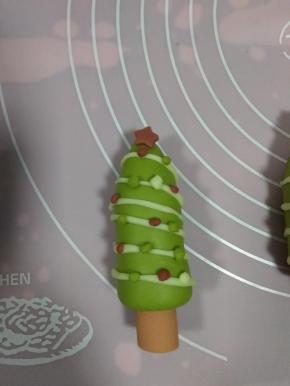 红色面团压出小五角星，放在顶端，剩下的面团，揉成小小的点放在圣诞树的白色线条上