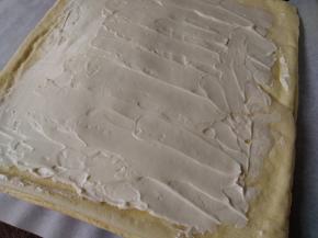 切去蛋糕的四条边，将打发好的淡奶油抹在蛋糕上