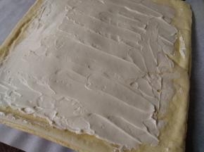 切去蛋糕的四条边，将打发好的淡奶油抹在蛋糕上