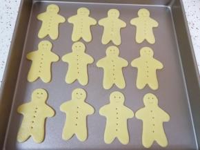 去掉边角料，将姜饼人饼干移至烤盘上，用牙签给姜饼人装饰出眼睛和扣子，吸管剪去一半装饰出姜饼人的嘴巴。剩下的边角料揉在一起继续做饼干。烤箱上下管160度提前预热。