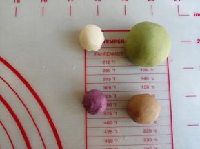 分割出27克的白面团加适量的菠菜粉，揉成绿色面团。9克白面团加可可粉，揉成棕色面团。4克白面团加紫薯粉，揉成紫色面团。用搓洗衣服的手法，使蔬果粉揉合进去，如果太难揉的话，可以加几滴水再揉