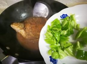 中火烧至汤汁剩下三分之一，中途翻面，放入泡椒