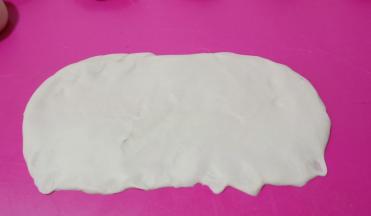 取一个面团从中间分别往上、往下擀开，翻面。将下面的边缘按薄压扁。