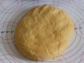 取出面团后，用手轻轻摁压排气。