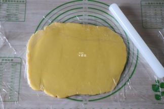 面团上下各铺一张保鲜膜，用擀面杖将面团擀成5mm左右厚的薄片；