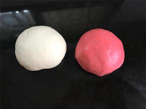 揉成光滑的面团后取出，分成250克和230克两个面团，把小的面团加入2克红曲粉揉成红色面团后，放温暖处分别进行发酵。