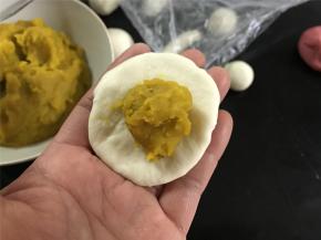 取一个大的白色面团，擀成圆面片后加入15克南瓜泥馅。
