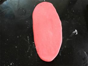 取一个红色面团，擀成椭圆形，用来包白色的包子。