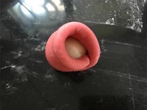 收口朝下，然后用红色椭圆形面片包起来，捏紧收口后，往上团。