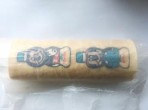 用擀面杖卷起底下的油纸，利用擀面杖将蛋糕卷卷起来，之后用擀面杖将油纸收紧，给蛋糕卷定形
