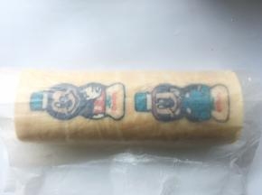用擀面杖卷起底下的油纸，利用擀面杖将蛋糕卷卷起来，之后用擀面杖将油纸收紧，给蛋糕卷定形
