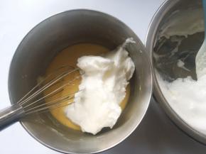 冰箱取出冷藏的蛋白霜，先取一部分蛋白霜加入到蛋黄糊中，用蛋抽翻拌均匀
