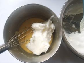 冰箱取出冷藏的蛋白霜，先取一部分蛋白霜加入到蛋黄糊中，用蛋抽翻拌均匀
