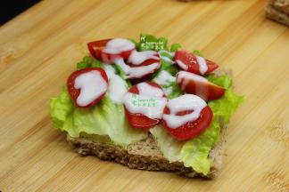 去边的吐司片，放一片生菜也，接着放切好的小番茄酱，再放沙拉酱；