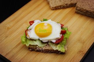 把刚刚煎好的鸡蛋放在上面，鸡蛋的大小要和吐司片一样，把多余的鸡蛋边角用锅铲切开；