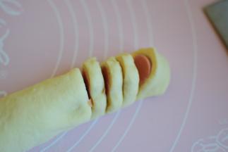 收口朝下，然后用刀把火腿肠切成小断，火腿肠的要切断，但是面团不能切断