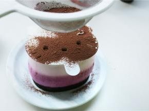 把学厨KT慕斯模具的表情卡放在在表面，用耐潮可可粉筛出表情。