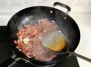 待翻炒至河虾颜色变红，加入2大匙料酒。
