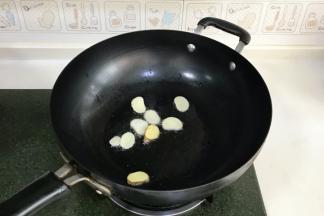 开火，往锅中倒入适量的食用油，接着入蒜片和姜片爆香。