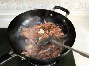 接着倒入清洗好的河虾，用锅铲翻炒片刻。