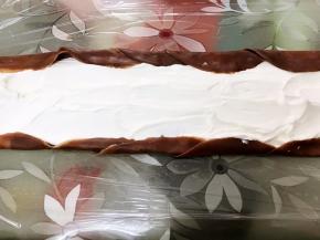 底部铺上保鲜膜，叠着摆放5到6张面皮，中间抹上淡奶油，两边不抹叠起