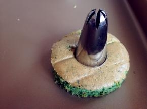 烘烤好的蛋糕取出，晾凉3分钟，再倒扣到烤架上，趁热撕去油纸。待放凉后，用圆形模具按压出12块蛋糕片，用花型的模具压出3块蛋糕片。其中9块的圆形蛋糕片，用大号的裱花嘴在中间压出圆形，你也可以用其他模具压出