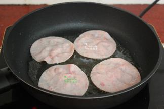 用平底锅，热锅，倒入少许油，放入切片火腿，煎至微黄，翻转另外一面继续煎至微黄