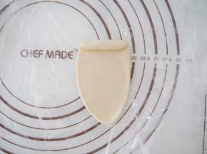 取一块水油皮在手心按成圆形，放上油酥包起来。收口朝下，擀成牛舌状