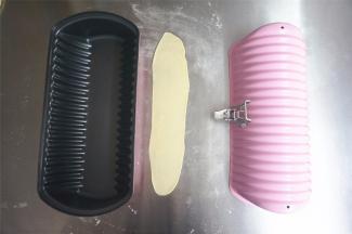 取一个15克的白面团，擀开成长条，长度比模具略短一些即可，放置在模具中央。