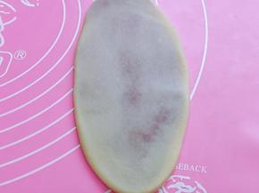 取一块面团，收口面朝下，用擀面杖擀成牛舌状，如图。