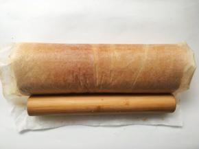 之后利用擀面杖将蛋糕卷卷起，卷好后收紧油纸，给蛋糕卷定下形，之后放冰箱冷藏15分钟
