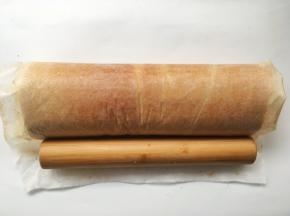 之后利用擀面杖将蛋糕卷卷起，卷好后收紧油纸，给蛋糕卷定下形，之后放冰箱冷藏15分钟
