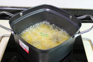 把鸡肉块放入小油炸锅，用筷子搅拌一下，防止粘在一起，炸至外皮金黄色。