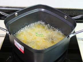 把鸡肉块放入小油炸锅，用筷子搅拌一下，防止粘在一起，炸至外皮金黄色。