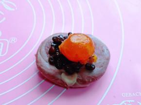 然后取一块面团，压扁，包入蜜豆馅，再放上咸蛋黄。