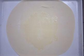把略大的面团擀成厚度为1mm的薄饼，在饼中间刷一层油，然后撒上适量干面粉