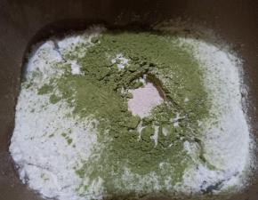 面包机先放入豆浆，对角放盐和糖，再放入高筋面粉和抹茶粉，中间挖个洞放入酵母。