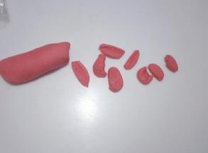 把红色面团分出8个豌豆粒大的的小面团，分别用来制作小猪的鼻子和耳朵部位