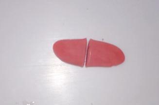 小红色面团搓长按扁，从中间一分为二，把尖端捏起，制作小猪的耳朵