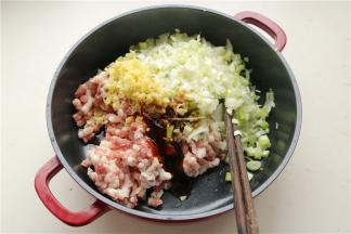 面团发酵的时候准备包子馅。先把葱姜切成末，和猪肉泥混合在一起，再加入蚝油、老抽、五香粉、盐和鲜鸡汁等所有调料，混合均匀。